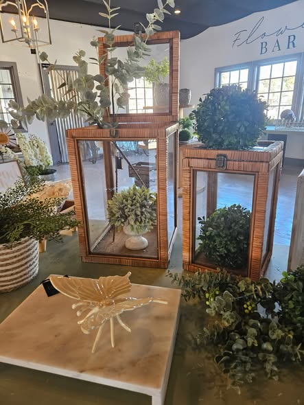 A styled Rayn interior vignette: rattan lanterns, eucalyptus greenery, brass chandelier and the Flower Bar wall